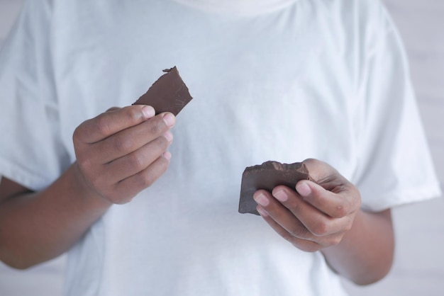 Jonge man eet donkere chocolade van dichtbij