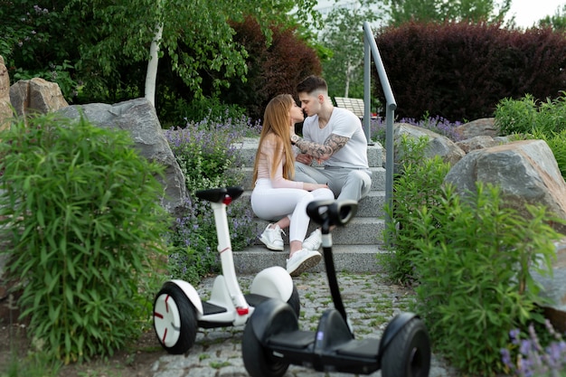 Jonge man en een vrouw kussen in het park Op de voorgrond hoverboard