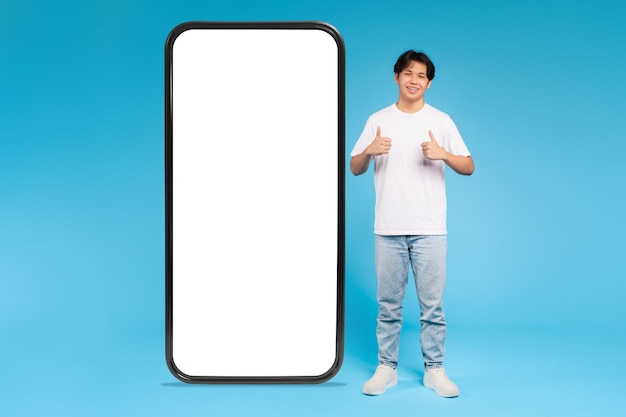 Jonge man en gigantische smartphone mockup blauwe achtergrond