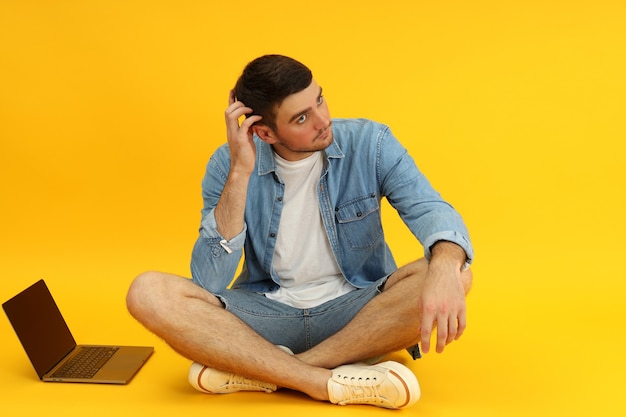 Jonge man en laptop op gele achtergrond.