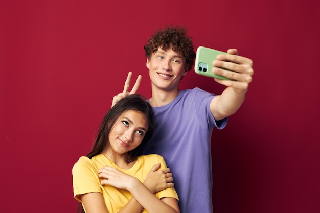 Jonge man en meisje in kleurrijke t-shirts met een telefoon-jeugdstijl