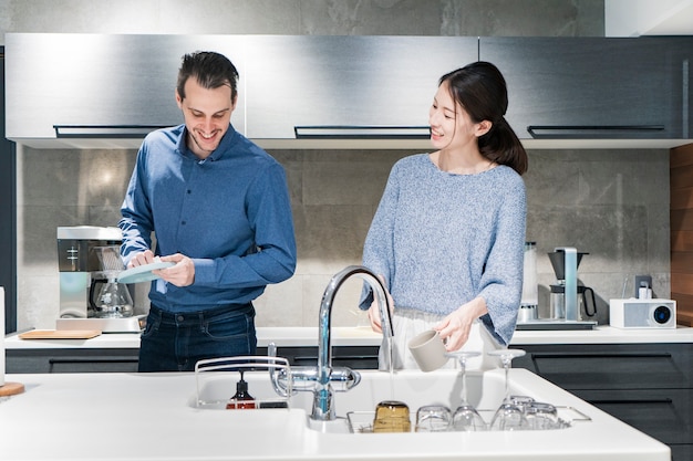 Jonge man en vrouw afwassen in de keuken met een glimlach