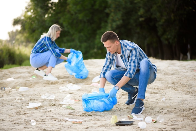 Jonge man en vrouw die afval buiten oppakken.