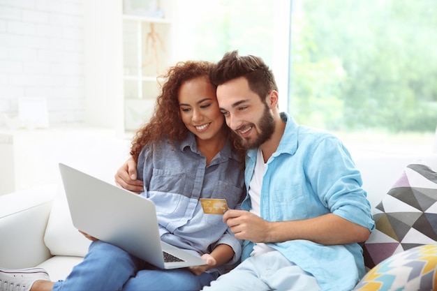 Jonge man en vrouw die creditcard en laptop gebruiken voor online winkelen