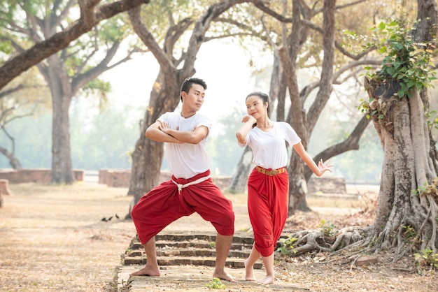Jonge man en vrouw die een traditionele Thaise dans uitoefenen