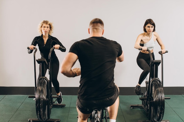 Jonge man en vrouw die luchtfiets gebruiken voor cardiotraining bij crosstrainingsgymnastiek