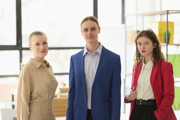 Jonge man en vrouw in formele outfits kijken in de camera staande tegen een helder raam succesvol