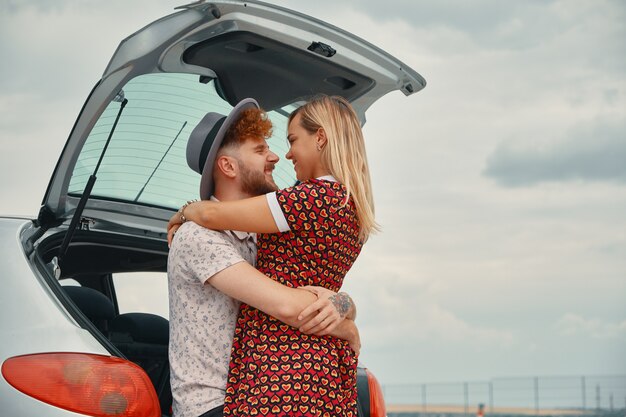 Jonge man en vrouw kussen in de kofferbak