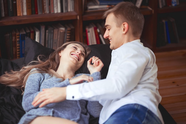 Jonge man en vrouw liggen in bed en hebben plezier