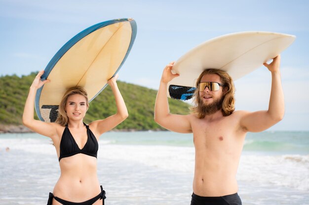 Jonge man en vrouw met surfplanken op hun hoofd en lopen de zee in om te surfen