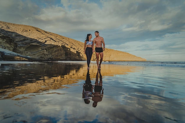 Jonge man en vrouw trainen op een gezonde manier buiten op het strand