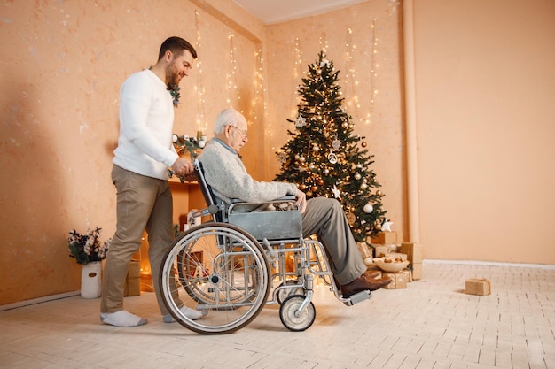 Jonge man en zijn oude vader in een rolstoel bij de kerstboom