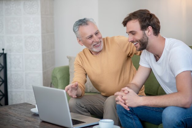 Jonge man en zijn vader kijken iets online en kijken betrokken