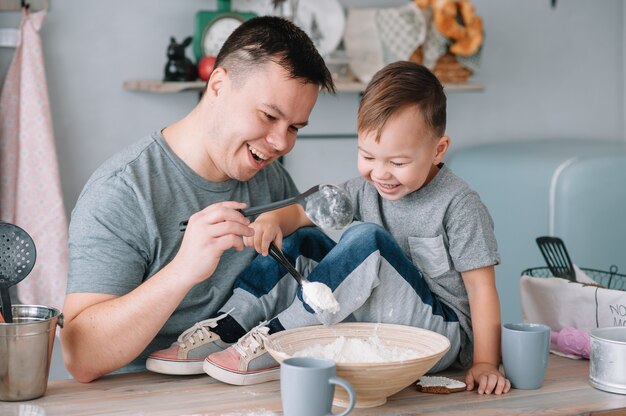 Jonge man en zijn zoon spelen in de keuken