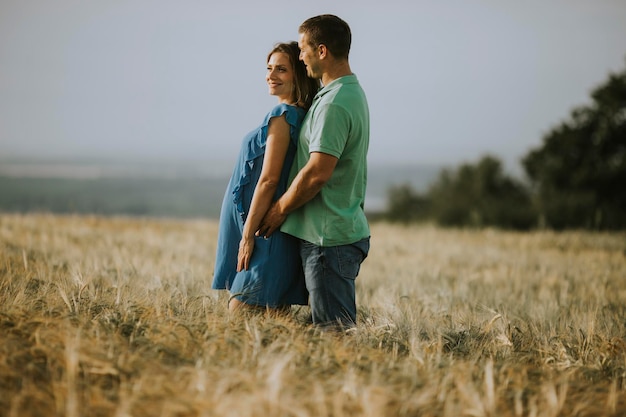 Jonge man en zijn zwangere vrouw in het zonnige zomerveld