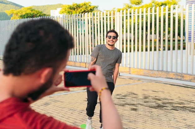 Jonge man filmt en maakt foto's van een vriend met een smartphone