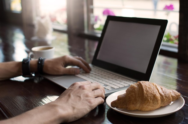 Jonge man freelancer werken vanuit een café met een laptop hipster man met behulp van moderne laptopcomputer tijdens het werken in een vintage loft close-up van mannelijke handen