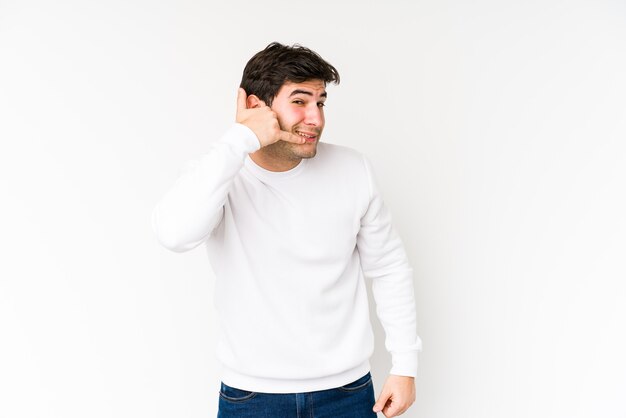 Jonge man geïsoleerd op een witte achtergrond met een gebaar van de mobiele telefoongesprek met vingers.