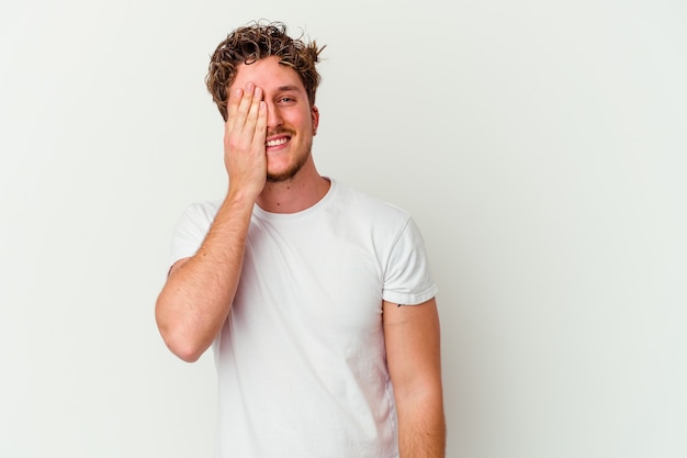 Jonge man geïsoleerd op een witte muur met plezier die de helft van het gezicht bedekt met palm