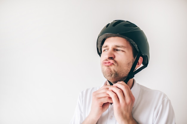 Jonge man geïsoleerd over witte muur. Ernstige vertrouwen man sluiten helm op zijn hoofd. Maak je klaar om te sporten.