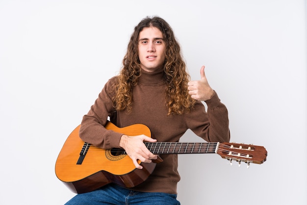 Jonge man gitaar spelen geïsoleerd glimlachend en duim opheffen