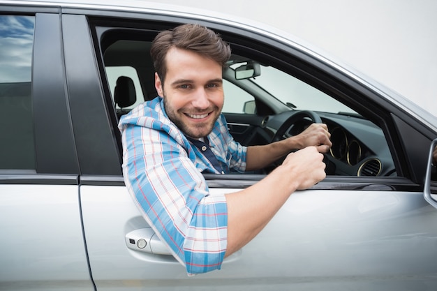 Jonge man glimlachend en rijden in zijn auto