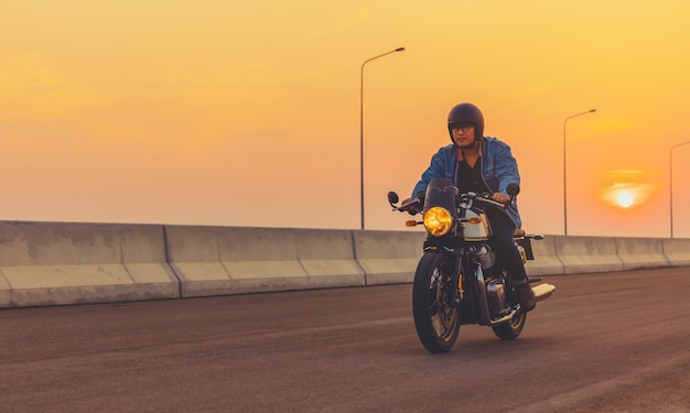 Jonge man grote fiets motorfiets rijden op asfalt hoge weg tegen bij zonsondergang