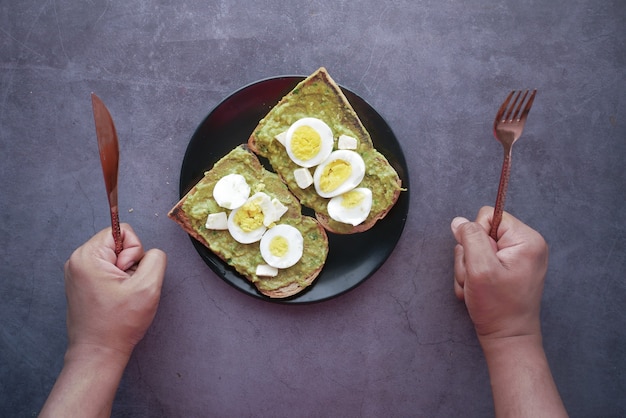 Jonge man hand wachten op het eten van avocado bruin brood