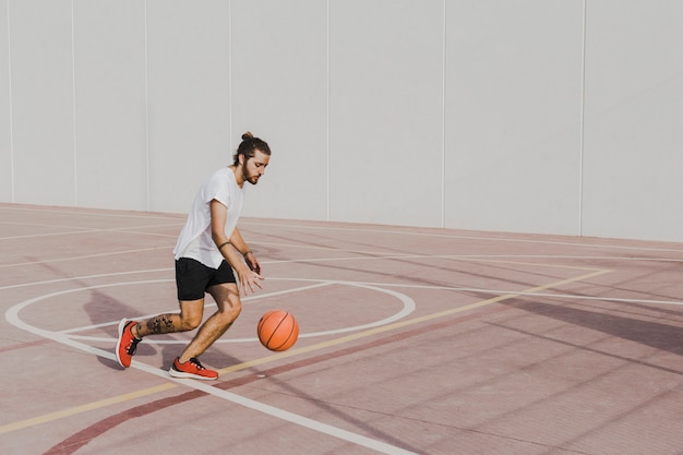 Foto jonge man het beoefenen van basketbal in de buitenlucht rechter