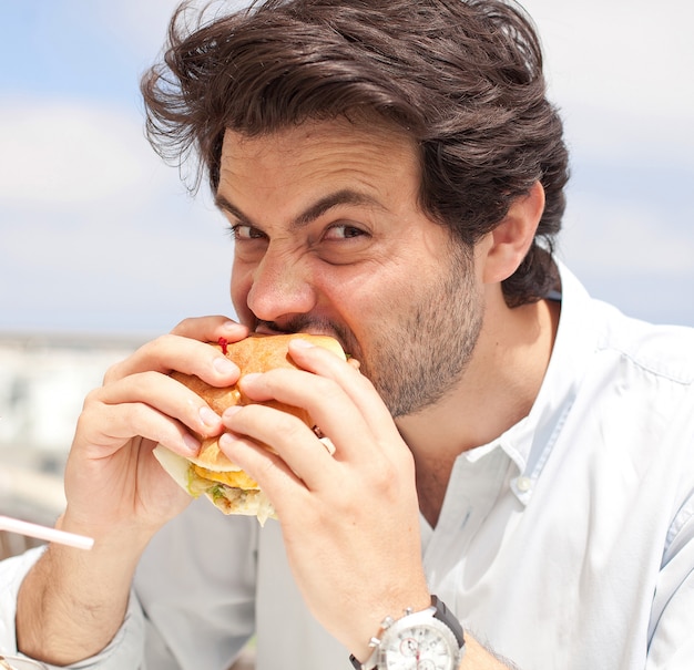 Jonge man het eten van een hamburguer