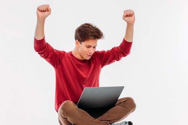 Jonge man het gelukkige winnen bij laptop op witte achtergrond