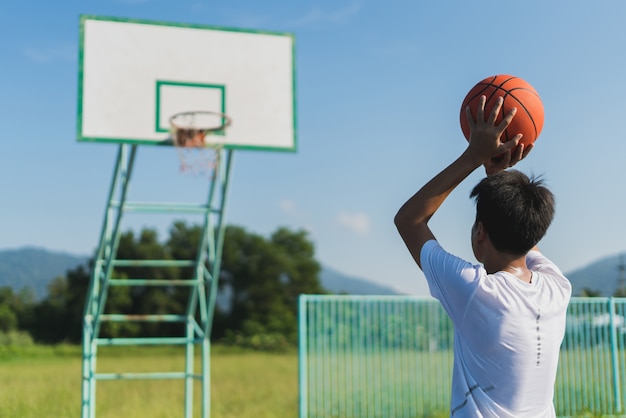 Foto jonge man het gooien van de bal in de basketbalring