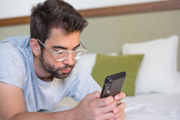 Jonge man het typen van een bericht in bed