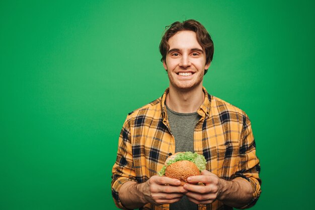 Jonge man houdt hamburger en geniet ervan