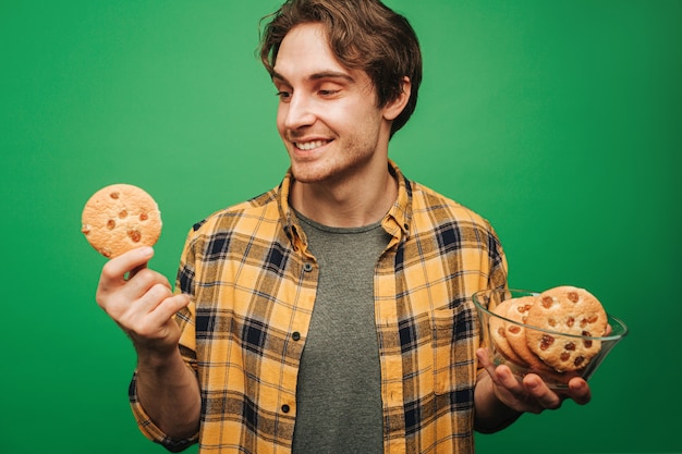 Jonge man houdt koekjes vast en voelt zich goed