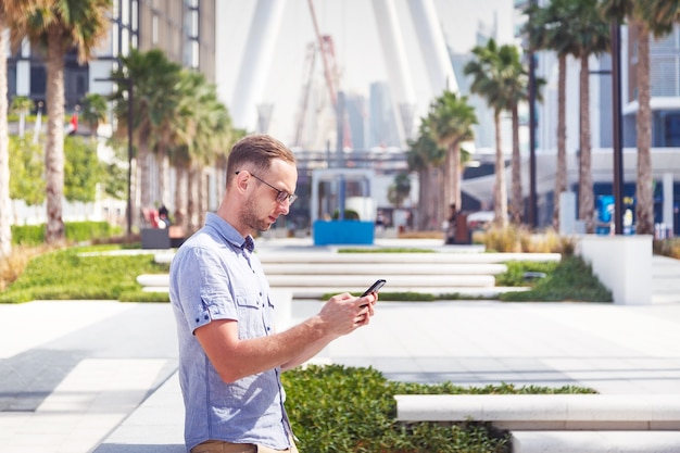 Jonge man in bril met zijn telefoon in Dubai