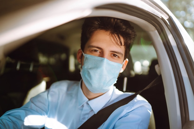 Jonge man in een beschermend masker in de auto zitten