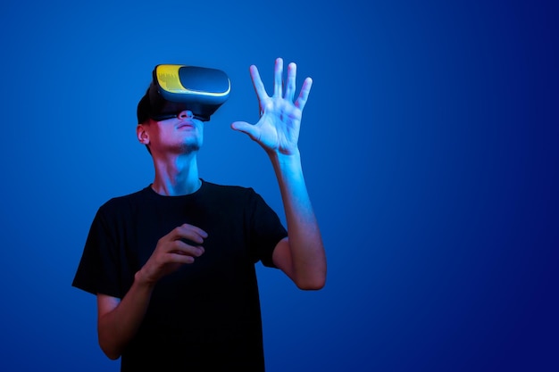 Jonge man in een vr-helm interageert met objecten in virtual reality in neonkleuren.