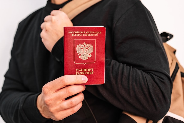 Jonge man in een zwart jasje toont een Russisch paspoort