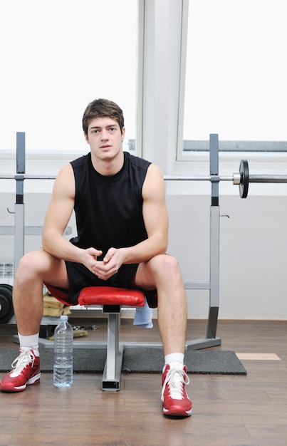 jonge man in fintess sportclub oefenen met gewichten en ontspannen?