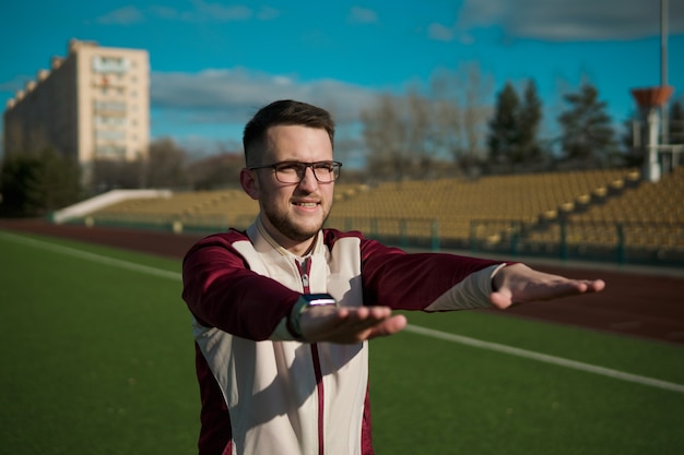Foto jonge man in glazen die zich uitstrekt over een stadion