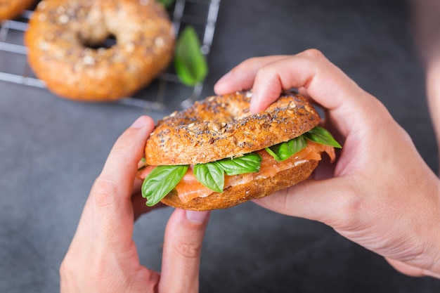 Jonge man in handen houden en klaar om bagels met gerookte zalm te eten