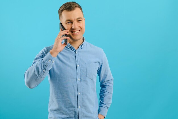 Jonge man in heldere kleurrijke slijtage praten op mobiele telefoon op blauwe achtergrond Trendy man heeft een gesprek Smartphone technologie concept