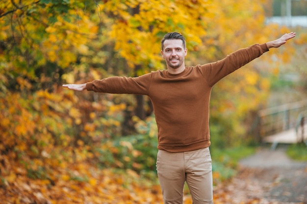 Jonge man in herfst park buiten spreidde zijn armen