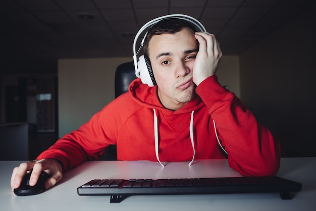 jonge man in hoofdtelefoon gebruik computers 's nachts. Gamer speelt games op de computer