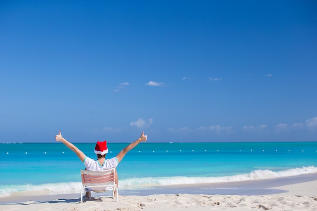 Jonge man in kerstmuts tijdens strandvakantie