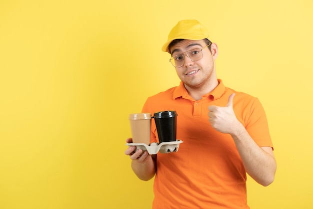 jonge man in oranje uniform met afhaalmaaltijden koffiekopjes.