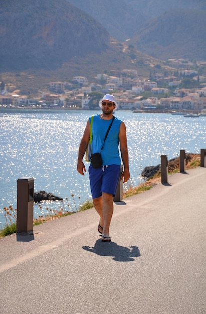 Jonge man in panama loopt naar het dorp Monemvasia in de Peloponnesos in Griekenland bij zonsondergang