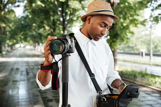 Jonge man in park met hoed, camera vast te houden