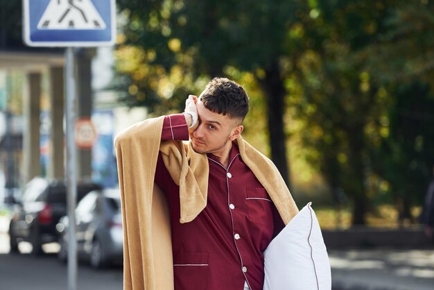 Jonge man in pyjama is buiten op straat Voelt zich slaperig